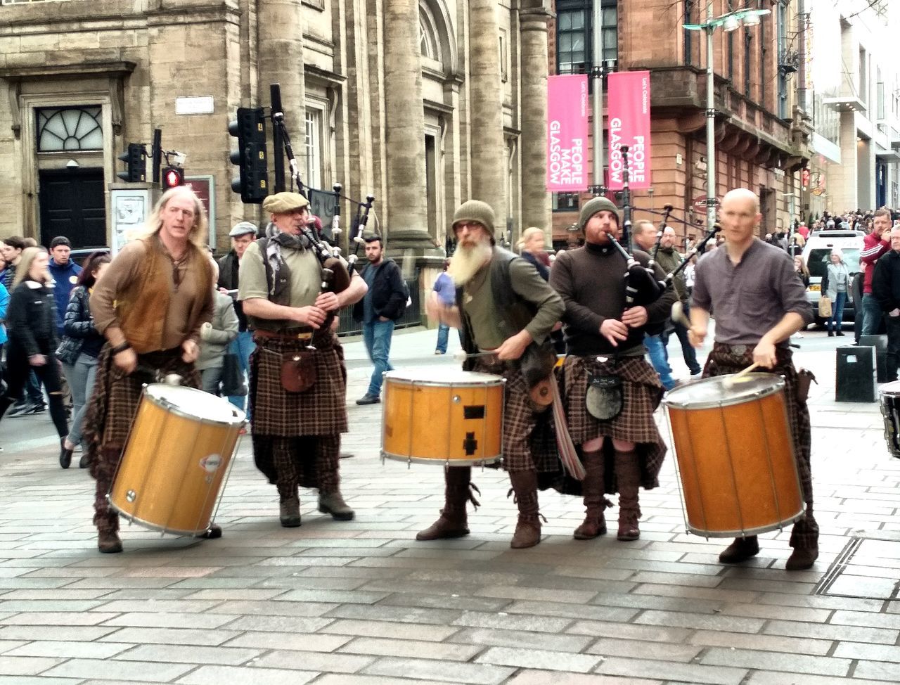 city, group of people, music, musical instrument, street, arts culture and entertainment, crowd, real people, building exterior, adult, architecture, full length, street performer, musician, musical equipment, people, day, artist, men, performance