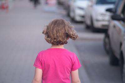 Rear view of girl walking on street in city