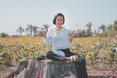 Portrait of smiling young woman sitting on field