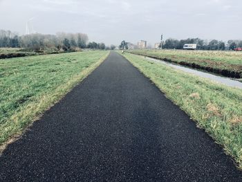 Road amidst field against sky