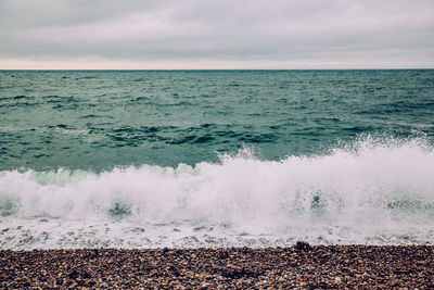 Waves splashing on shore against sky