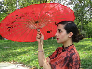 Young woman looking away while standing on tree