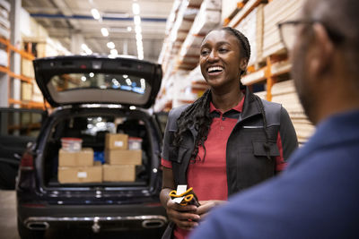 Happy saleswoman standing with customer in warehouse at hardware store