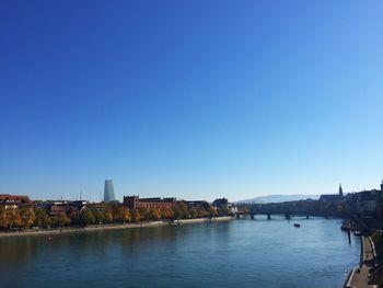 River amidst buildings against clear blue sky