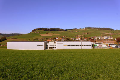 Houses on field against clear blue sky