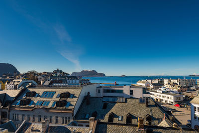 High angle view of townscape by sea against blue sky