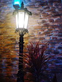 Low angle view of illuminated light bulb against brick wall