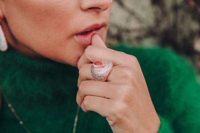 Close-up of woman wearing ring sitting outdoors