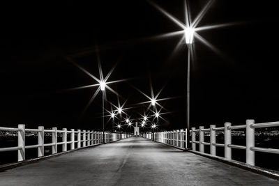 Illuminated pier against sky at night