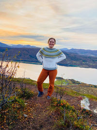Portrait of smiling woman standing on mountain against sky