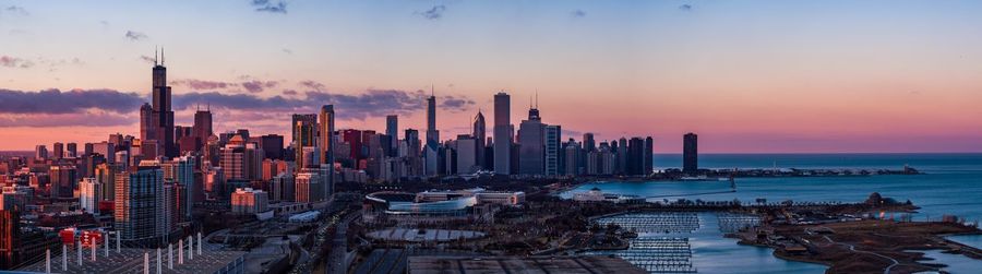 Panoramic view of sea and buildings against sky during sunset