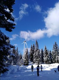 People walking on snow covered land against sky