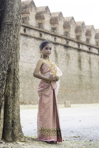 Full length of woman standing against tree