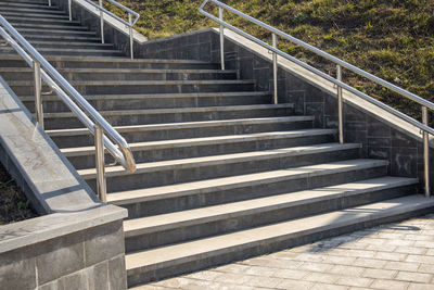 Outdoor concrete steps on a modern city staircase with metal railings on a sunny day, outdoors,