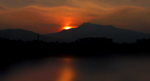 Scenic view of silhouette mountains against orange sky