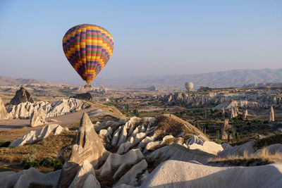 Hot air balloon flying over landscape against clear sky