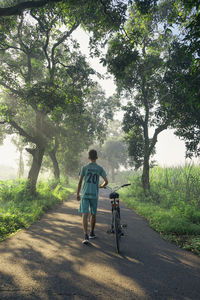 Rear view of man riding bicycle on field