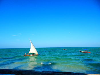 Sailboat sailing in sea against clear blue sky