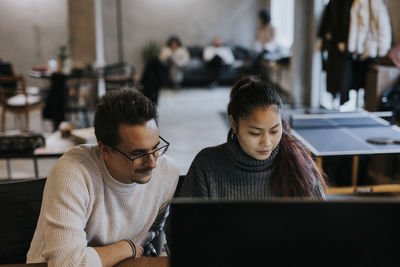 Multiracial male and female hackers working on laptop in startup company