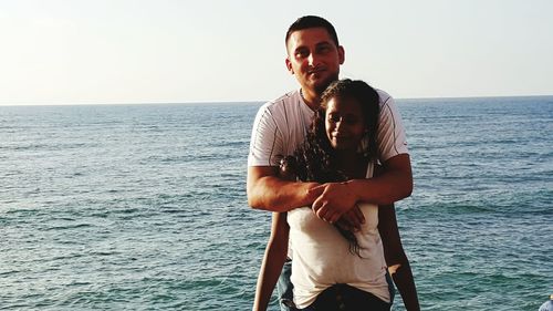 Portrait of couple standing against sea