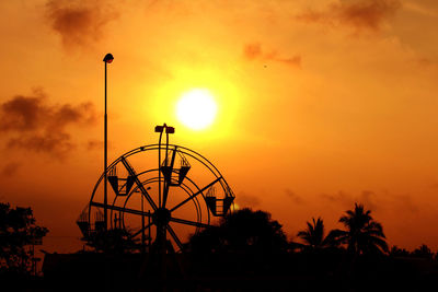 Silhouette ferris wheel against orange sky