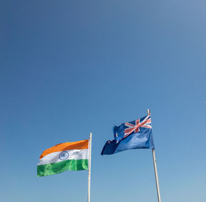 Low angle view of flags against clear blue sky