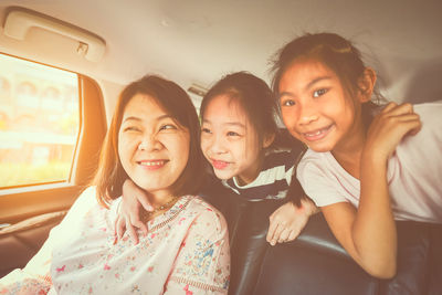 Happy siblings with mother sitting in car