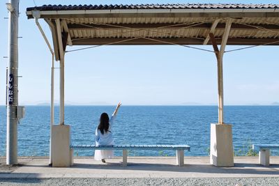 Rear view of woman standing by sea against sky
