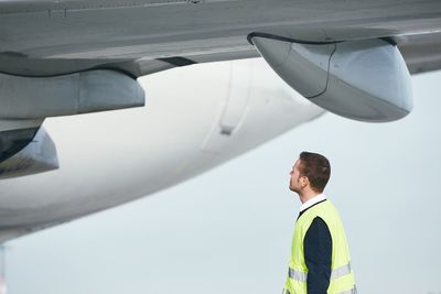 Side view of young man looking at airplane