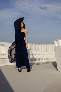 Full length of woman standing on railing against sky