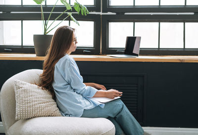 Young woman sitting on sofa at home