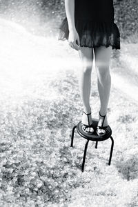 Low section of woman standing on stool outdoors