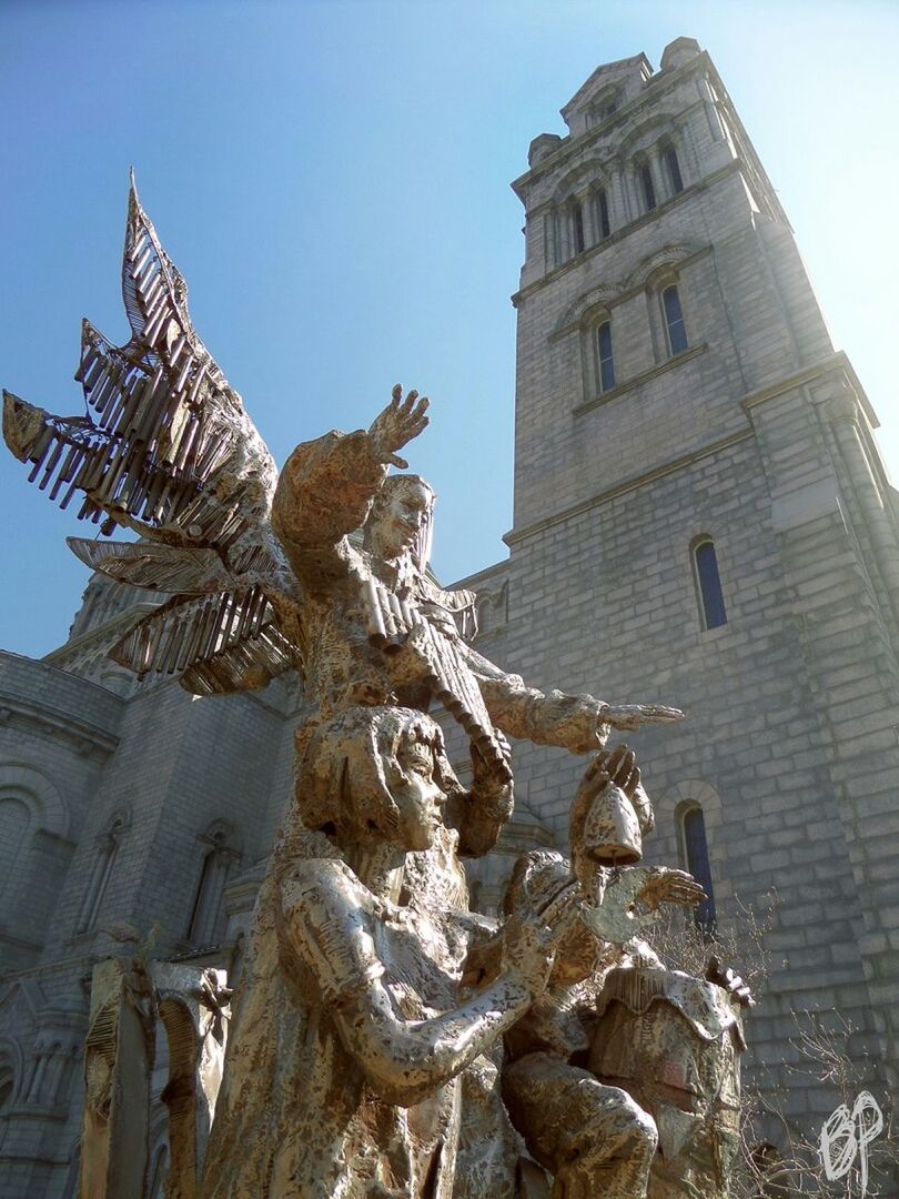 low angle view, architecture, building exterior, built structure, art and craft, religion, sculpture, statue, art, human representation, creativity, spirituality, place of worship, clear sky, sky, history, church, carving - craft product