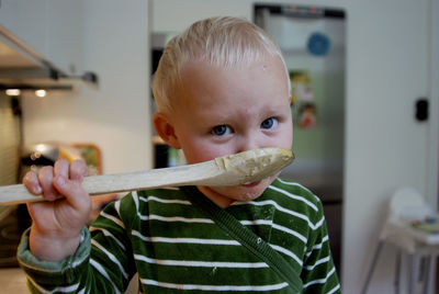 Portrait of cute boy holding camera at home