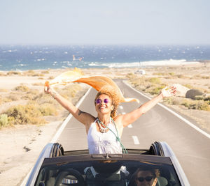 Portrait of young woman sitting in boat on beach against sky