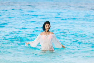 Portrait of smiling woman in swimming pool against sea