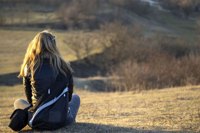 Rear view of woman sitting on field