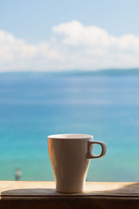 Close-up of coffee cup on table against sea