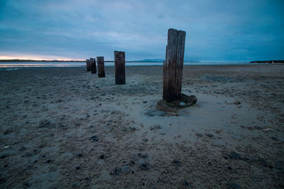 Wooden posts on beach against sky