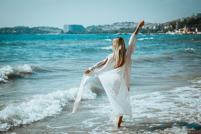 Woman wearing shirt while wading in sea