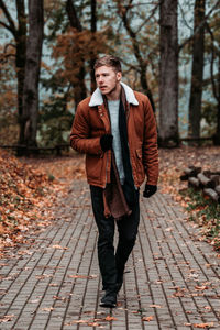 Young man walking on footpath in park during autumn