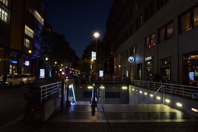 Illuminated street amidst buildings at night