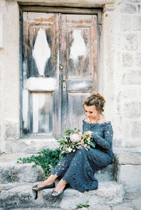 Side view of young woman sitting against wall