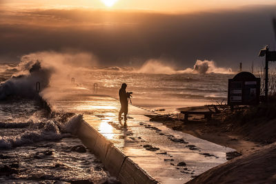 Man standing on beach against sky during sunset