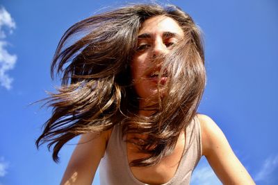 Portrait of beautiful woman against blue sky