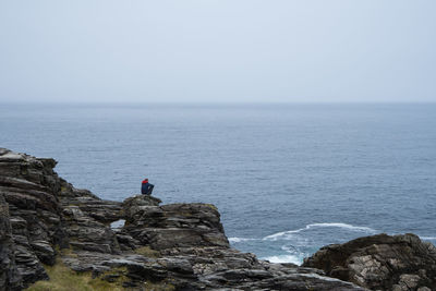 Man sitting on rock against sea at beach
