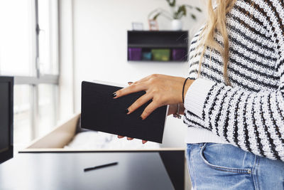 Midsection of woman using laptop at home