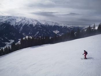 Man skiing on snowcapped mountain against sky