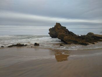 Rock formation on beach against sky