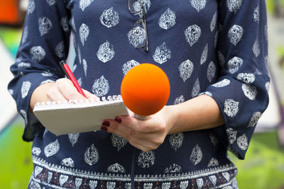 Midsection of female journalist writing on note pad